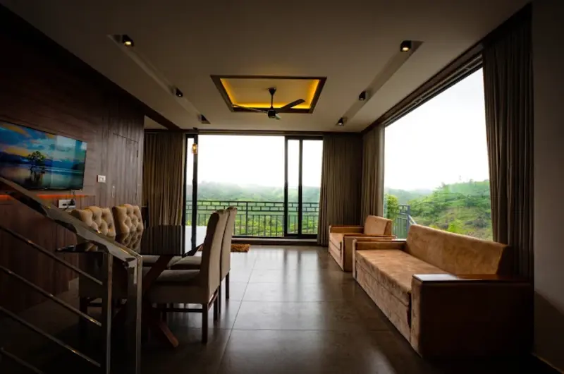 Luxury suite living area with floor-to-ceiling window view of Vagamon hills