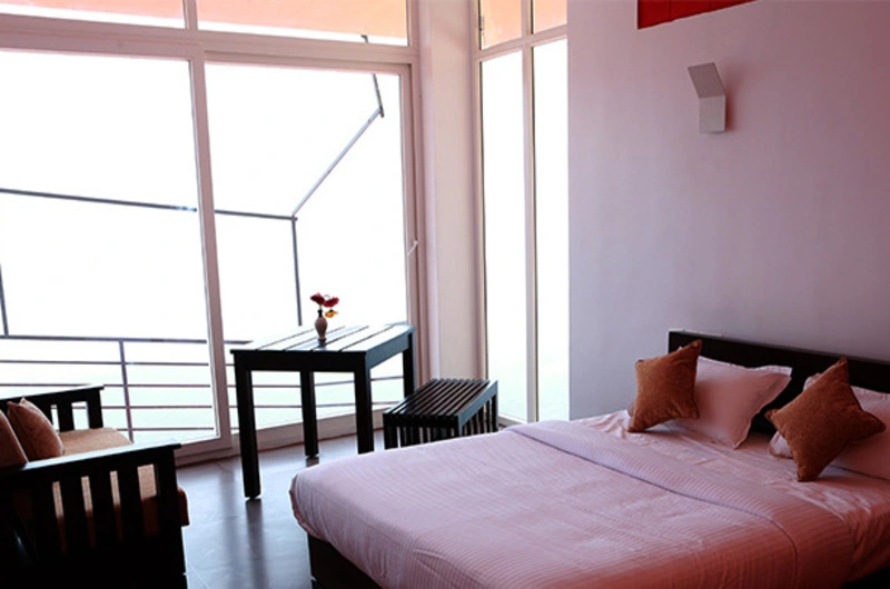 Resort bedroom with large glass door leading to private balcony at Vaga Nakshathra Suites