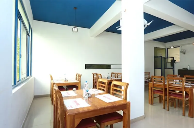 Spacious guest restaurant and dining area with wooden furniture at Vaga Nakshathra Suites