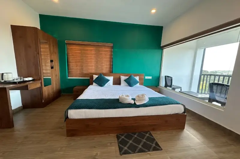 Deluxe resort room with green feature wall and large scenic window at Vagamon Hill Chimes