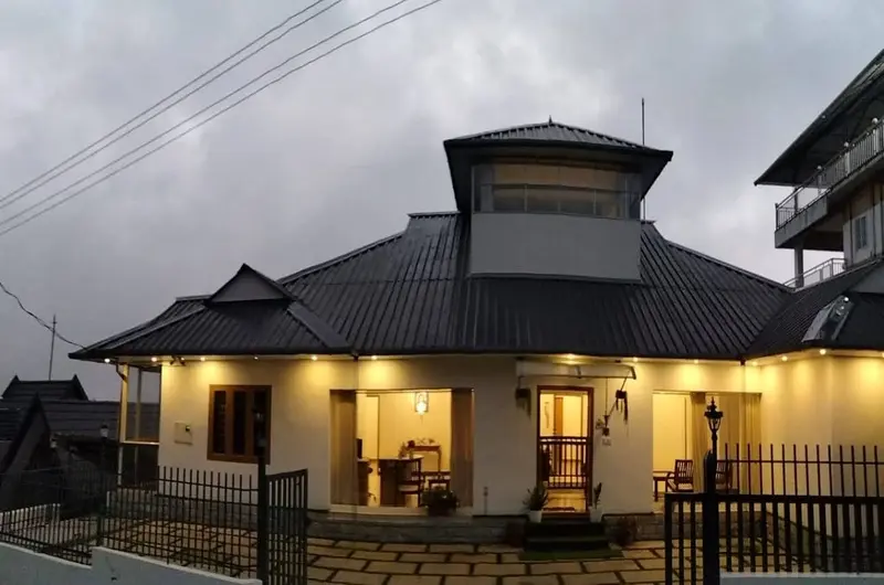 Vagamon Hill Chimes resort building exterior lit up at evening against mist-covered hills