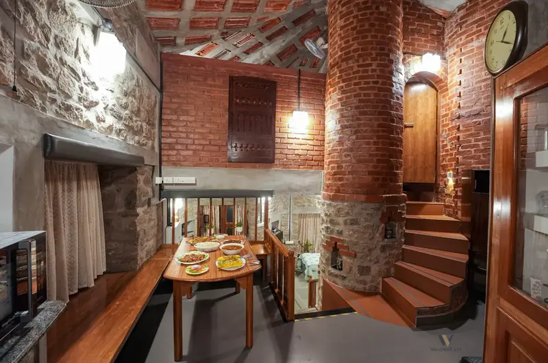 Rustic lounge interior featuring stone walls and staircase to loft at Stone Haven by Wanderease