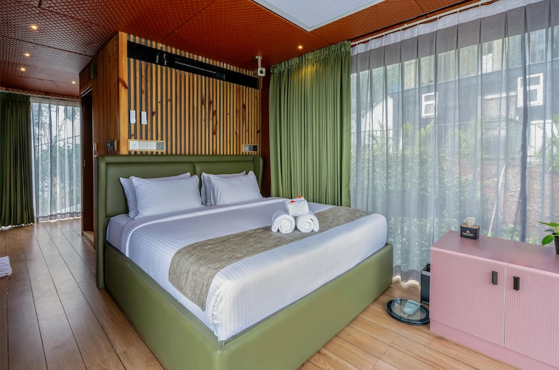 Elegantly furnished guest room with green headboard accent wall and modern wooden interiors in Vagamon
