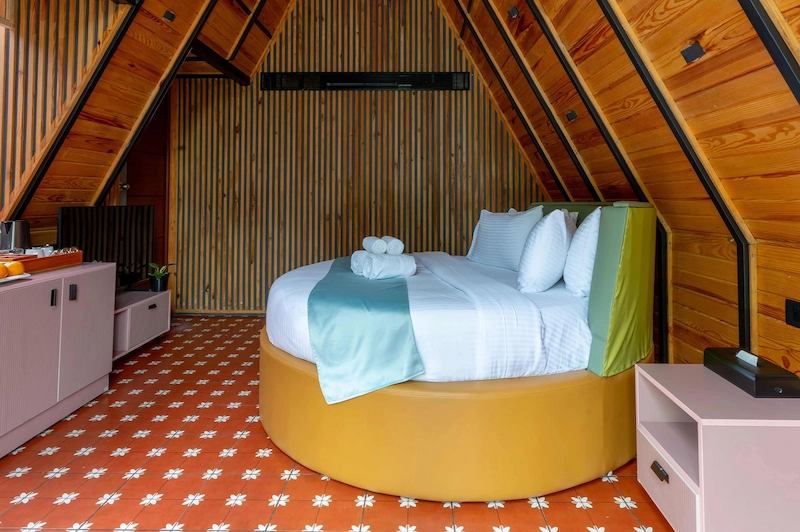 Spacious A-frame bedroom suite with circular bed and modern wooden interiors in Vagamon