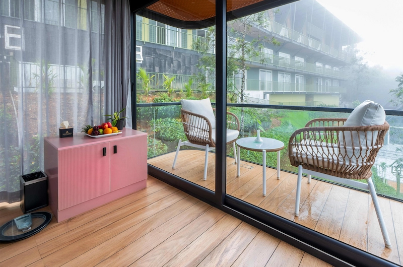 Luxury guest bedroom with plush pink armchair and glass balcony view at Santuario Resort Vagamon