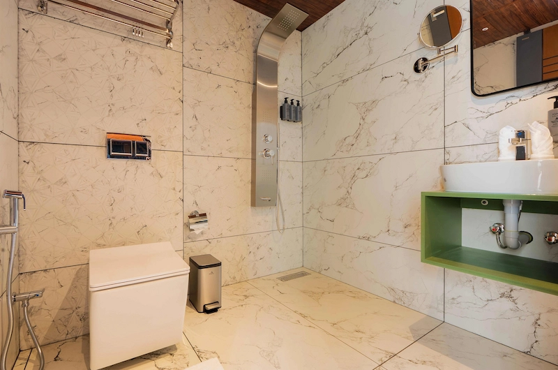 Spacious marble-finished resort bathroom featuring walk-in shower enclosure and modern fittings in Vagamon