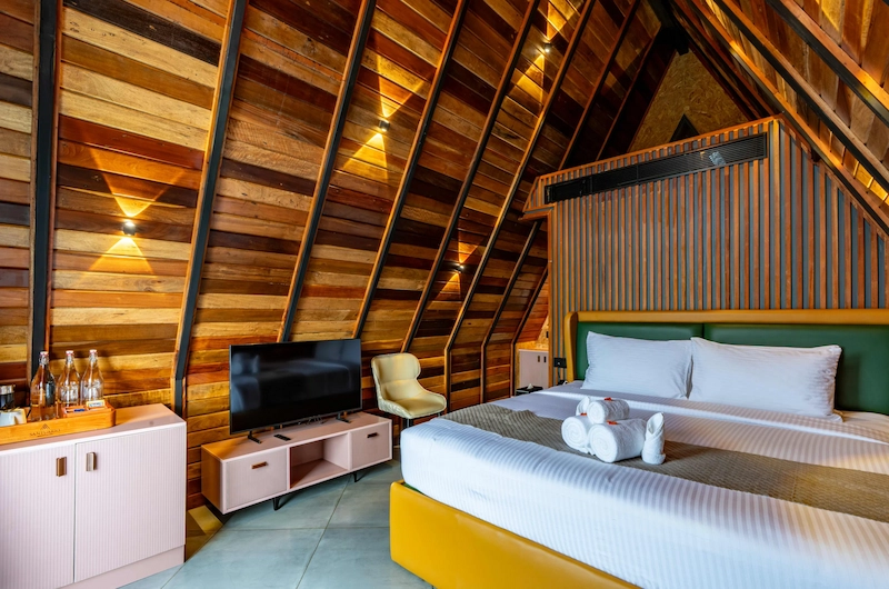 Spacious A-frame bedroom suite with comfortable double bed and rustic wooden architecture in Vagamon