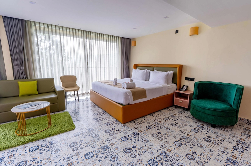 Spacious guest bedroom with king bed, sofa lounge, and floor-to-ceiling windows in Vagamon