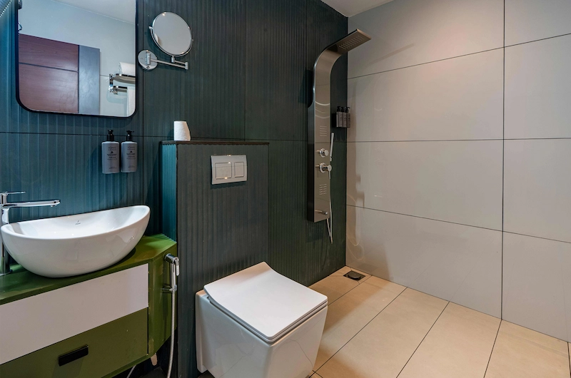 Modern bathroom interior with dark tiled walls, floating sink, and contemporary fixtures in Vagamon