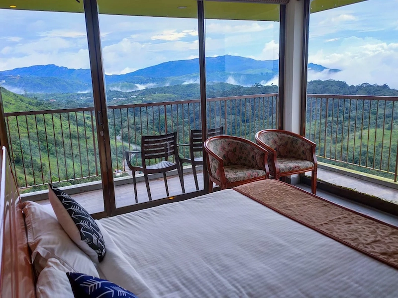 Spacious guest bedroom balcony featuring glass railings and panoramic mountain views