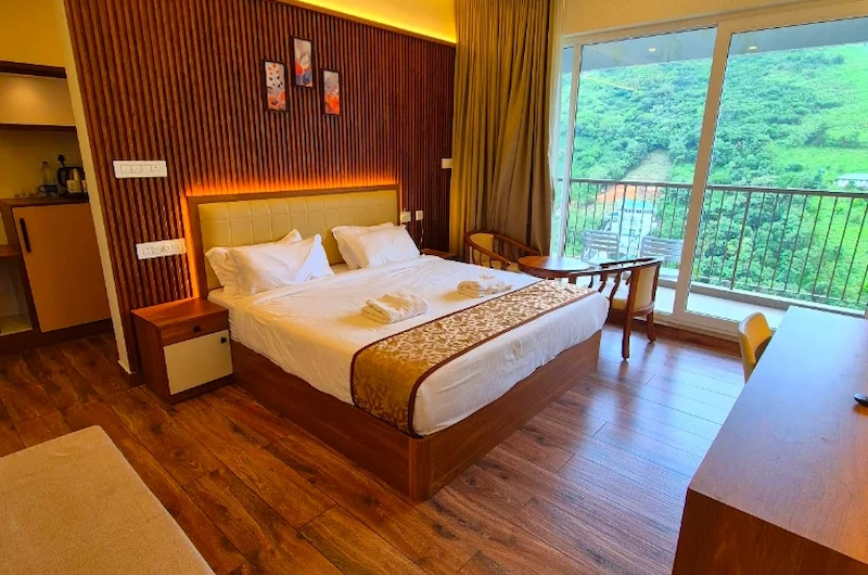 Modern hotel room interior with plush king bed, wooden accent wall, and floor-to-ceiling valley view window