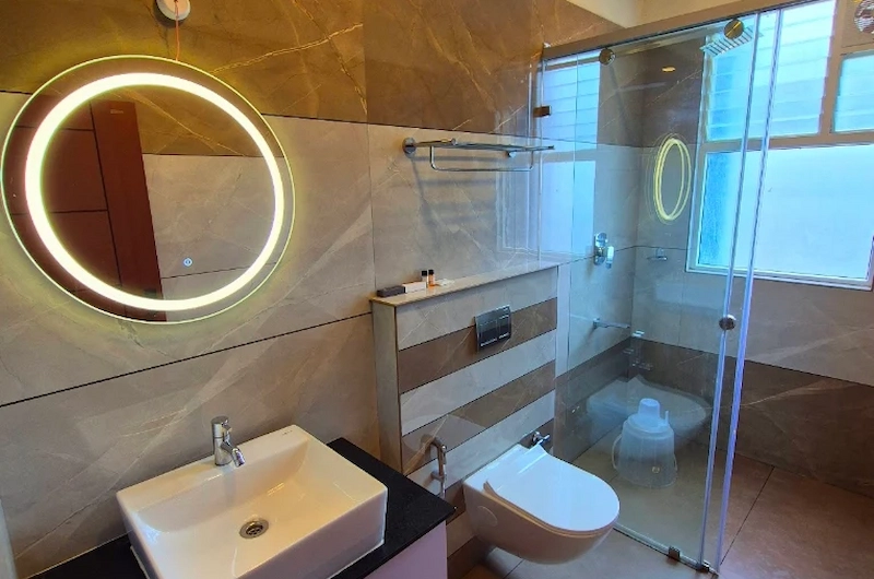 Modern hotel bathroom with LED mirror, glass shower partition, and clean fixtures