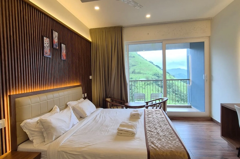 Cozy family bedroom suite with dual beds and large window offering scenic green views in Vagamon