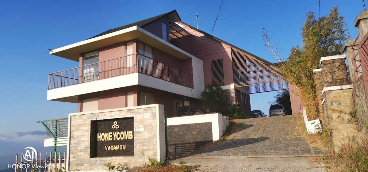 Exterior view of Honeycomb resort building with paved driveway and scenic mountain backdrop in Vagamon