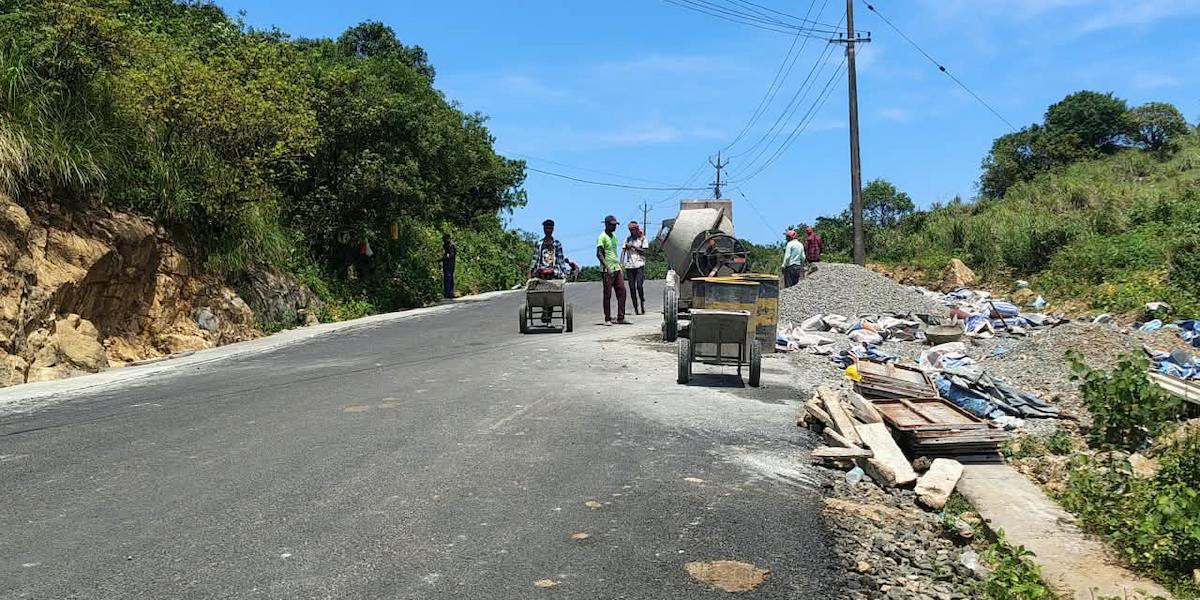 Road maintenance work with construction equipment and workers on hill road to Vagamon
