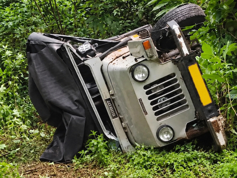 Overturned off-road tourist jeep on side near green foliage after Vagamon accident