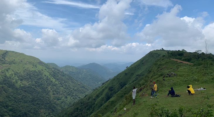 Tourists trekking along scenic green mountain hills in Vagamon Kerala
