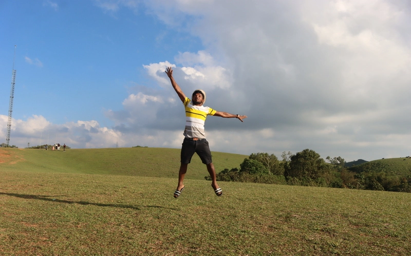 Person enjoying team retreat on scenic green meadow hills in Vagamon Kerala