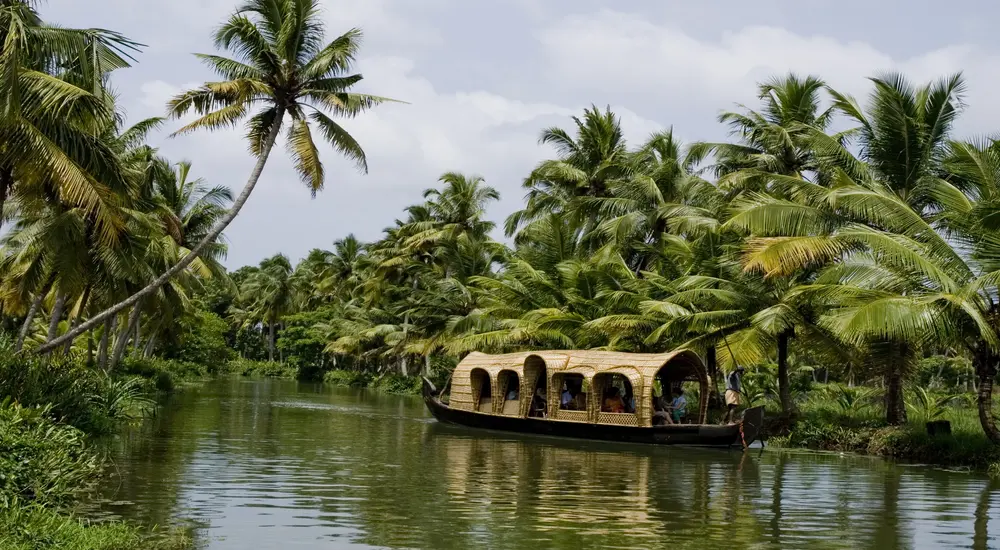 Luxury houseboat cruising through a palm-fringed canal along Kerala backwaters