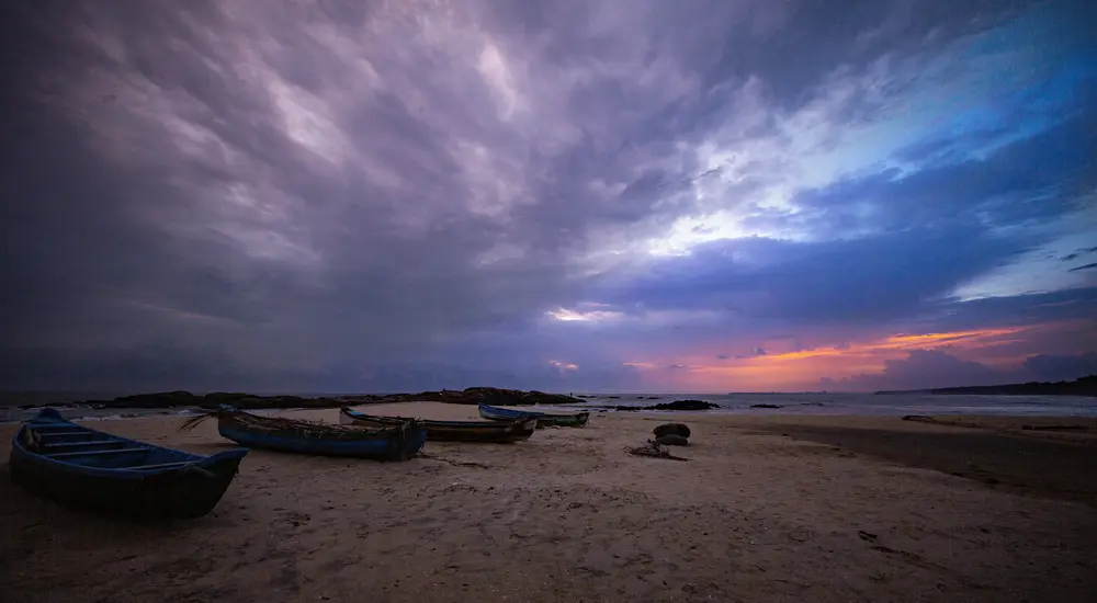 Dramatic sunset view over Kerala coastal beach with fishing boats