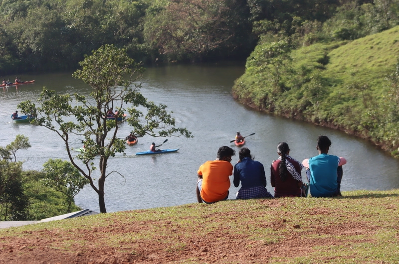 Honeymoon couple enjoying scenic river views from a grassy hill in Vagamon