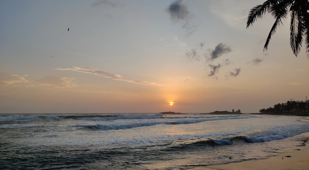 Golden sunset view over peaceful ocean waves on Kovalam beach in Kerala