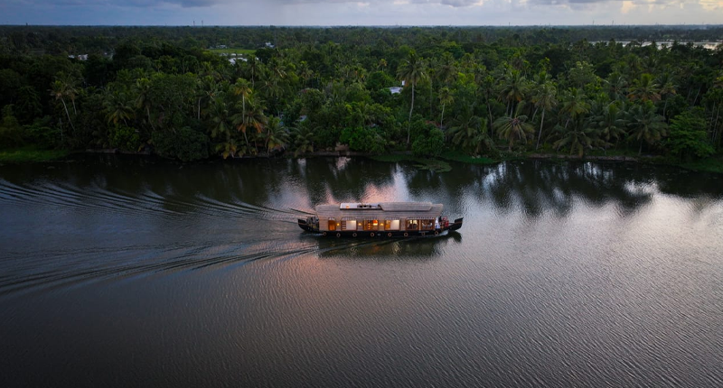 Aerial view of a houseboat cruising along lush green backwater canals in Alleppey Kerala